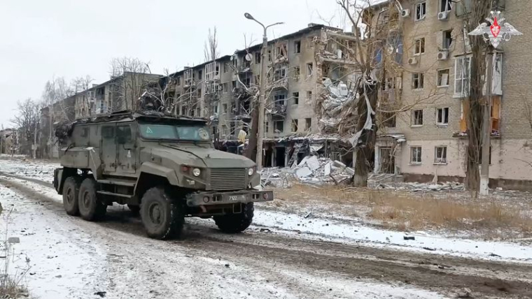 Un véhicule militaire russe passe devant des bâtiments résidentiels endommagés dans la ville d'Avdiivka