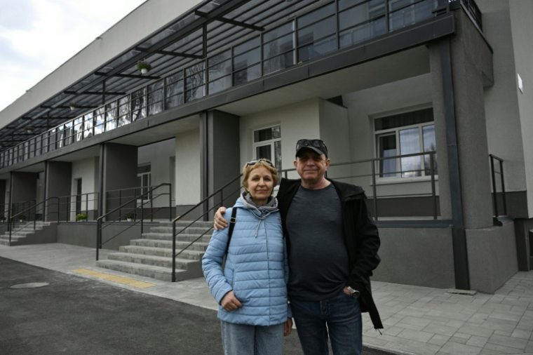 Maryna et son époux Volodymyr, déplacés par la guerre, posent devant un bâtiment rénové dans la ville de Slavoutytch dans le nord de l'Ukraine, le 25 avril 2026  ( AFP / Genya SAVILOV )