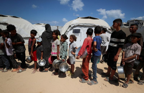 Des Palestiniens attendent de recevoir de la nourriture préparée par une cuisine caritative près des tentes où ils ont trouvé refuge après avoir été déplacés par l'offensive militaire israélienne, à Gaza