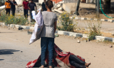 Une enfant palestinienne se tient devant le corps d'une personne tuée en venant chercher des vivres dans un site de distribution de la Fondation humanitaire de Gaza (GHF) soutenue par Israël et les Etats-Unis, dans le centre de la bande de Gaza, le 4 août 2025 ( AFP / - )