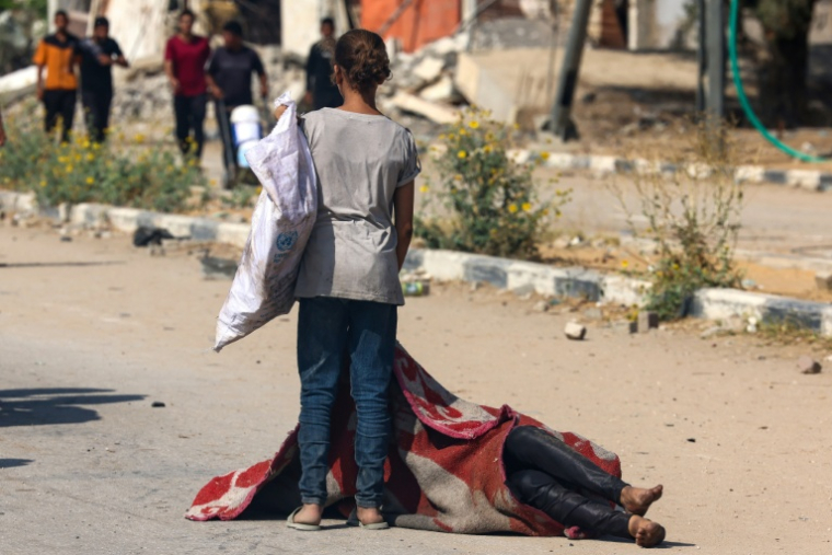 Une jeune Palestinienne près du corps d'une personne tuée à proximité d'un point de distribution d'aide, le 4 août 2025 dans le centre de la bande de Gaza ( AFP / - )