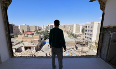 Un homme regarde les immeubles résidentiels endommagés par des frappes à Karaj, au sud-ouest de Téhéran, le 3 avril 2026 en Iran ( AFP / ATTA KENARE )