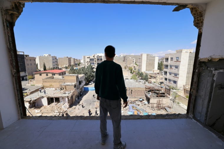 Un homme regarde les immeubles résidentiels endommagés par des frappes à Karaj, au sud-ouest de Téhéran, le 3 avril 2026 en Iran ( AFP / ATTA KENARE )