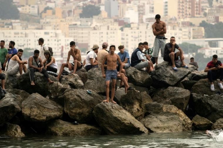 Des migrants rassemblés sur des rochers à Ceuta après avoir traversé la frontière par la mer, le 31 juillet 2026 ( AFP / JORGE GUERRERO )