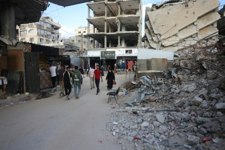 Des Palestiniens marchent près d'immeubles détruits avant l'Aïd al-Adha, la fête du sacrifice, à Khan Younès, dans le sud de la bande de Gaza, le 26 mai 2026 ( AFP / Bashar Taleb )