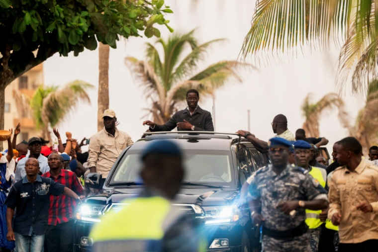 Le président sénégalais Bassirou Diomaye Faye (au centre) salue ses partisans depuis le toit ouvrant de son véhicule à l'issue d'une cérémonie de lancement de Kiiraay, son nouveau parti, dans le quartier des Almadies à Dakar, le 25 juillet 2026 ( AFP / SEYLLOU )