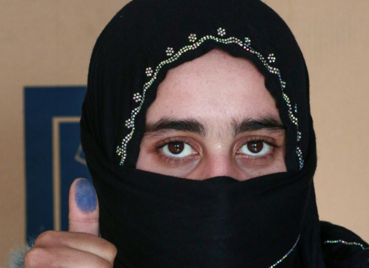 Une Irakienne déplacée montre son doigt taché d'encre après avoir voté dans un bureau de vote, avant les élections législatives du 11 novembre, dans un camp du nord de l'Irak, le 9 novembre 2025 ( AFP / Safin HAMID )