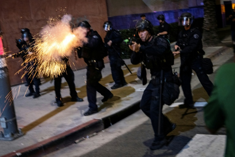 Des policiers de Los Angeles, dont l'un fait feu avec une arme non létale, le 30 janvier 2026 dans la ville californienne lors d'une manifestation contre la police de l'immigration ( AFP / ETIENNE LAURENT )