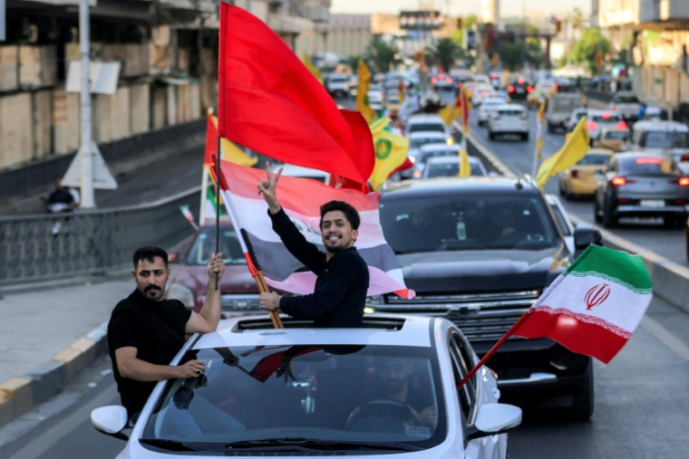 Des jeunes circulent en véhicules en brandissant des drapeaux irakiens, iraniens, libanais et du Hezbollah, lors des célébrations qui ont suivi l'annonce d'un accord mettant fin à la guerre entre l'Iran et les États-Unis, le 15 juin 2026 à Bagdad ( AFP / AHMAD AL-RUBAYE )