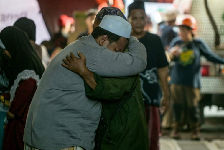 Des proches des écoliers disparus se réconfortent pendant que les opérations de recherche et de sauvetage se poursuivent à l'internat islamique Al Khoziny à Sidoarjo, dans la province de Java oriental, le 1er octobre 2025 ( AFP / Juni KRISWANTO )