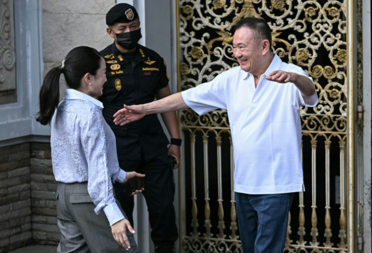 L'ancien Premier ministre Thaksin Shinawatra salue sa fille Paetongtarn Shinawatra à sa sortie de prison, le 11 mai 2026 à Bangkok ( AFP / Lillian SUWANRUMPHA )
