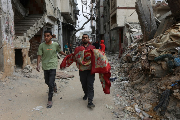 Un Palestinien porte le corps d'une victime à Choujaïya à Gaza-ville, le 9 avril 2025 ( AFP / Omar AL-QATTAA )