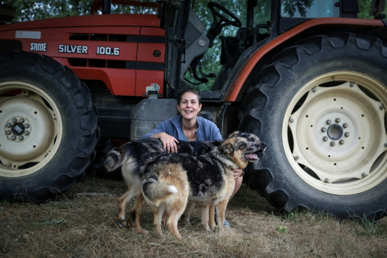 L'agricultrice Élodie Lac pose avec ses chiens dans sa ferme biologique à Cézac (Lot), le 19 août 2025 ( AFP / Valentine CHAPUIS )