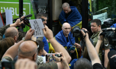 Des prisonniers de guerre ukrainiens libérés enveloppés dans le drapeau national débarquent d'un bus à leur arrivée après un échange de prisonniers dans la région de Tcherniguiv, le 26 juin 2025, en Ukraine ( AFP / Genya SAVILOV )