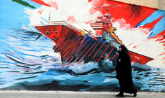 Une femme passe devant une fresque murale anti-américaine et anti-israélienne à Téhéran, le 21 avril 2026. ( AFP / ATTA KENARE )