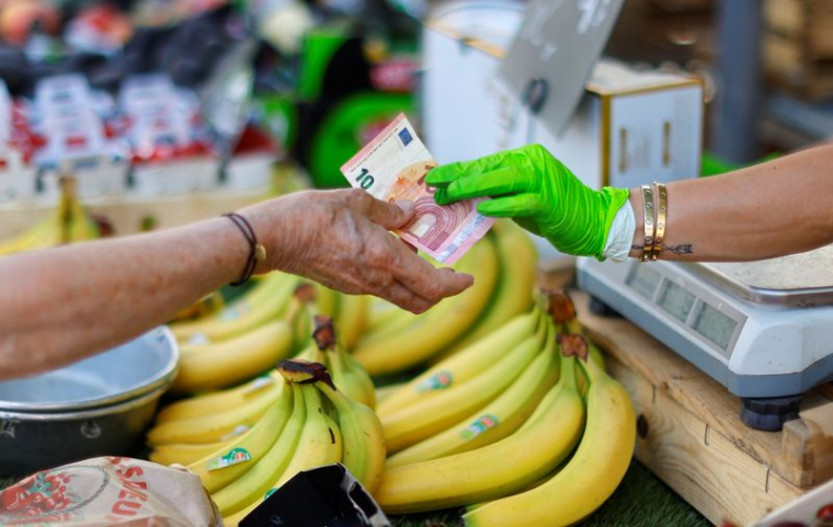 Une cliente paie avec un billet de dix euros dans un marché local à Nice