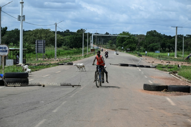 Des enfants à vélo franchissent la frontière entre la Côte d'Ivoire et le Burkina Faso, le 12 octobre 2025 à Koquiénou, près de Doropo ( AFP / Issouf SANOGO )