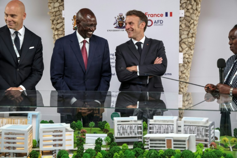 Le président français Emmanuel Macron (d) et le président kényan William Ruto (g) devant une maquette du projet de complexe d'ingénierie et de sciences qui sera construit avec le soutien du gouvernement français sur le campus de l'Université de Nairobi, lors du sommet Africa Forward, le 11 mai 2026 au Kenya ( AFP / Ludovic MARIN )