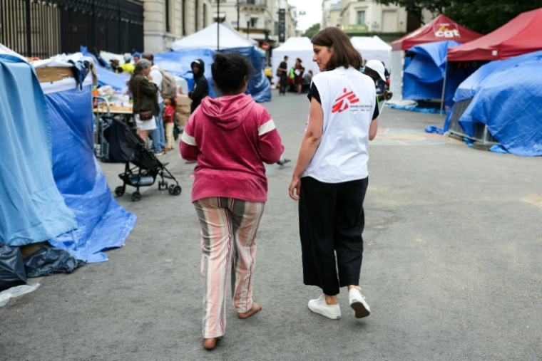 Un membre de Médecins sans frontières parle avec une migrante dans un camp de fortune installé en plein centre de Paris le 21 août 2026 ( AFP / Thomas SAMSON )