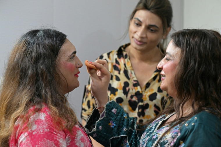 Reem Sharif (g), militante des droits des transgenres, se fait maquiller par Bunty (d), transgenre et danseuse, sous le regard de leur amie transgenre Nisha (c), chez lune amie à Rawalpindi, le 10 juillet 2025 au Pakistan ( AFP / Aamir QURESHI )