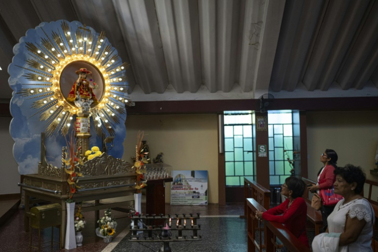 Des fidèles prient devant une représentation du Miracle de l'Enfant Jésus dans l'église de Santa Maria Magdalena, à Eten, dans la région de Lambayeque, au nord du Pérou, le 10 mai 2025. ( AFP / ERNESTO BENAVIDES )