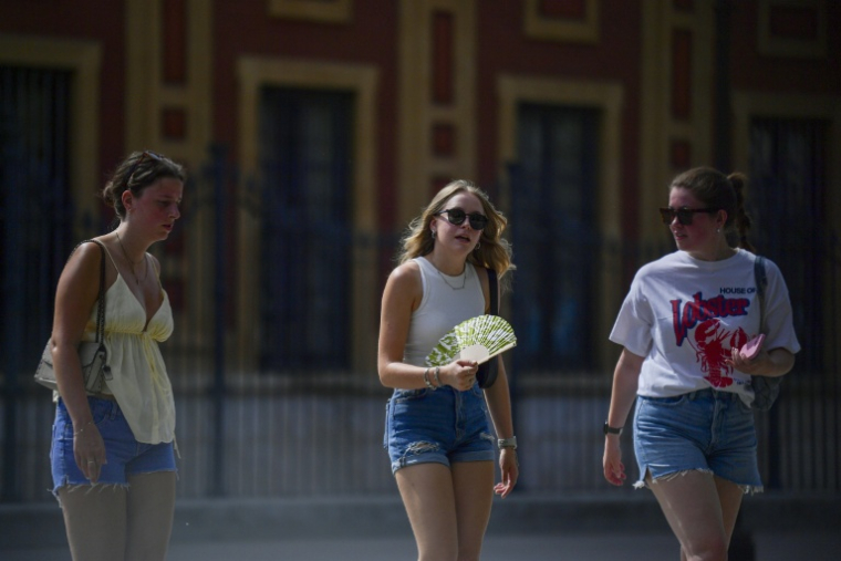 Des jeunes femmes tentent de se rafraichir à Séville le 28 juin 2025 ( AFP / CRISTINA QUICLER )
