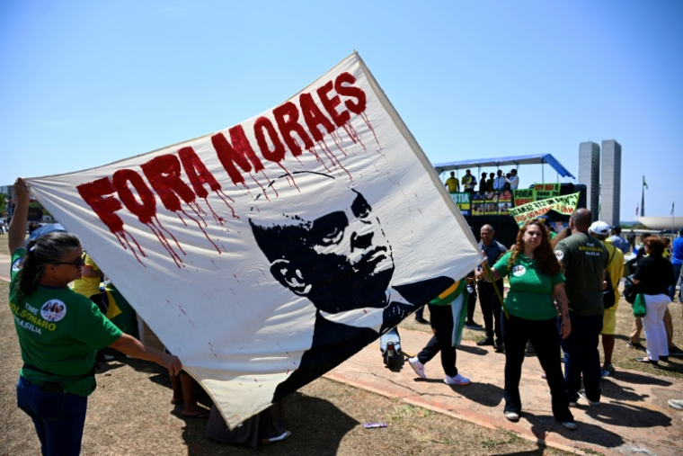 Des manifestants portent un drapeau réclamant le départ du juge de la Cour suprême Alexandre de Moraes, le 15 septembre 2026 à Brasilia ( AFP / Evaristo Sa )