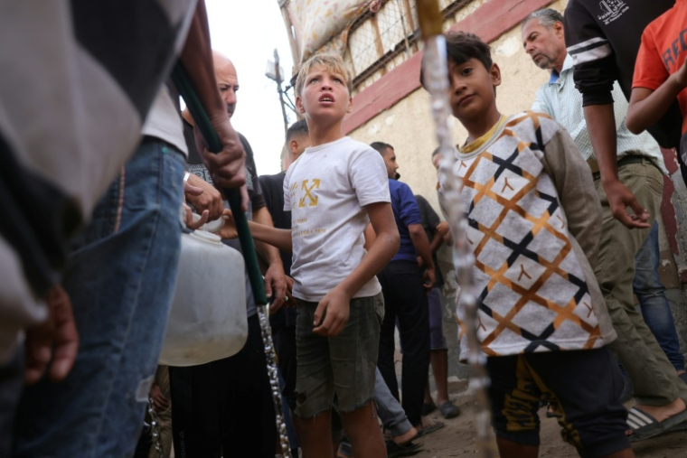 Des enfants palestiniens déplacés par les frappes israéliennes remplissent des jerrycans d'eau à Al-Zawayda, dans le centre de la bande de Gaza, le 9 octobre 2025. ( AFP / BASHAR TALEB )