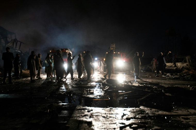 Des pompiers afghans et des agents de sécurité talibans travaillent sur le site d'un incendie après des frappes pakistanaises, le 16 mars 2026 à Kaboul ( AFP / Wakil KOHSAR )