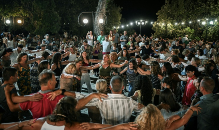 Locaux et vacanciers dansent un "panigiri", une tradition en Grèce, au village du Prophète Elie, sur l'île d'Ikaria, le 20 juillet 2025  "panigiri" in the village of Profitis Ilias on the Greek Aegean island of Ikaria, on July 20, 2025. The "panigiri" are patron saint festivals that mark the summer in all the villages of the Greek islands and on the mainland, deeply rooted in Greek culture. Celebrations and dances often continue until dawn, attracting large crowds and many tourists. Each "panigiri" is associated with the feast day of a local patron saint, such as the Prophet Elijah on July 20 and Saint John on August 28. Its origins date back to 1821. ( AFP / Aris MESSINIS )