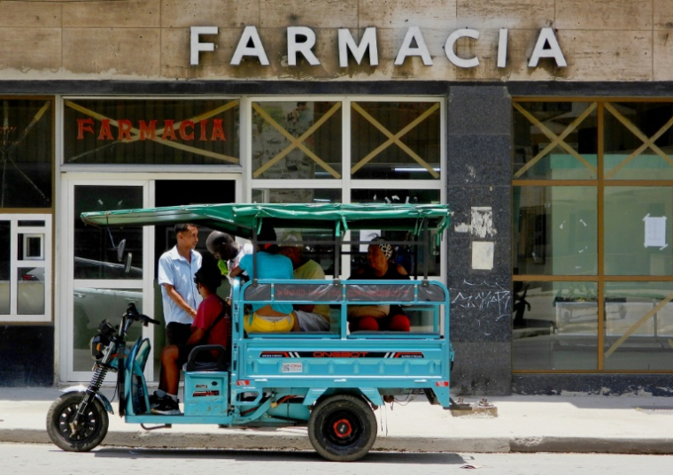 Des Cubains passent devant une pharmacie à La Havane, le 2 juillet 2025 ( AFP / ADALBERTO ROQUE )