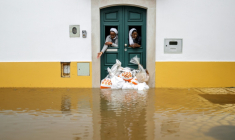 Deux religieuses observent la rue depuis une porte renforcée par des sacs de sable pendant les indondations liées à la tempête Leonardo à Alcacer do Sal, au sud du Portugal, le 4 février 2026 ( AFP / PATRICIA DE MELO MOREIRA )