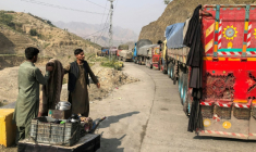 Un vendeur de thé près des véhicules immobilisés aux abords de la ville frontalière de Torkham entre le Pakistan et l'Afghanistan, le 19 octobre 2025 ( AFP / Basit GILANI )