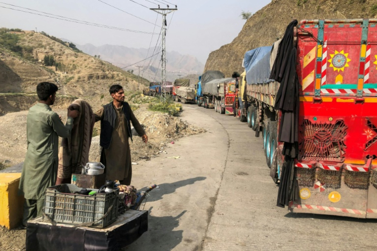 Un vendeur de thé près des véhicules immobilisés aux abords de la ville frontalière de Torkham entre le Pakistan et l'Afghanistan, le 19 octobre 2025 ( AFP / Basit GILANI )