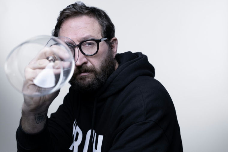 L'auteur de BD Terreur Graphique tient un verre vide à l'occasion de la sortie de son livre relatant ses 25 ans d'alcoolisme et son combat pour la sobriété, le 13 janvier 2026 à Paris ( AFP / Joel Saget )