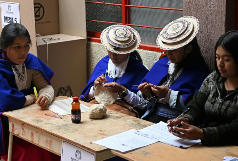 Des femmes misak autochtones font du crochet en attendant les électeurs dans un bureau de vote lors de l'élection présidentielle à la réserve indigène de Guambia, dans le département du Cauca, en Colombie, le 31 mai 2026 ( AFP / Joaquin SARMIENTO )