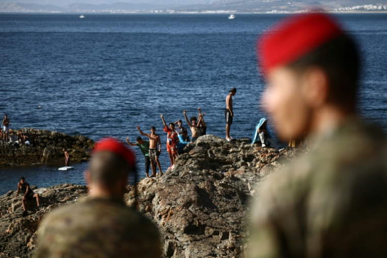 Des militaires espagnols regardent un groupe de jeunes gens sur des rochers à proximité du poste-frontière de l'enclave espagnole de Ceuta, le 2 août 2026 à Ceuta ( AFP / Henry NICHOLLS )
