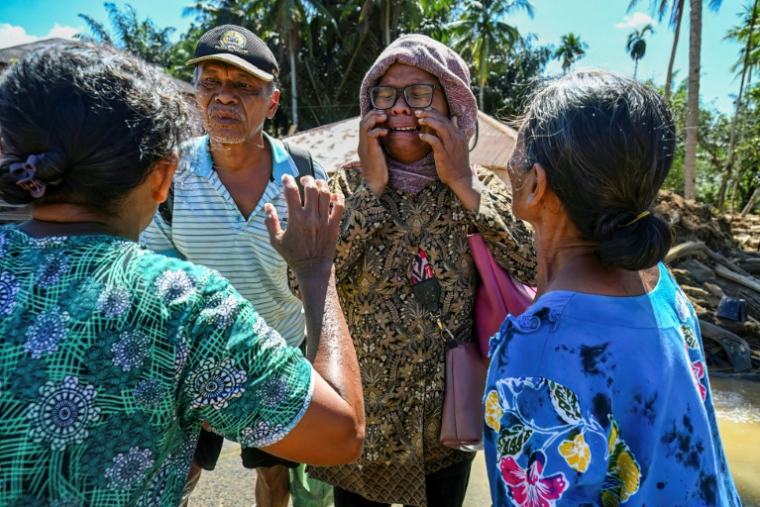 Une femme retrouve ses proches après que leur village a été frappé par une crue éclair à Tukka, dans le district de Tapanuli central, province de Sumatra du Nord, le 3 décembre 2025 ( AFP / YT Hariono )