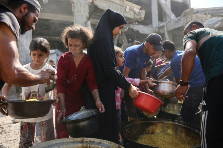 Des Palestiniens déplacés attendent de recevoir de la nourriture à l'extérieur de la mosquée Imam al Shafi'i en ruines, où des familles ont trouvé refuge, dans le quartier de Zeitoun à Gaza, le 23 octobre 2025 ( AFP / Omar AL-QATTAA )