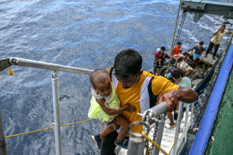 Des passagers montent à bord  du ferry Kalighat, l'unique lien entre Chowra et Car Nicobar, deux minuscules morceaux de l'archipel indien des Andaman-et-Nicobar, en plein cœur de l'océan Indien, le 30 mars 2026 ( AFP / R. Satish BABU )