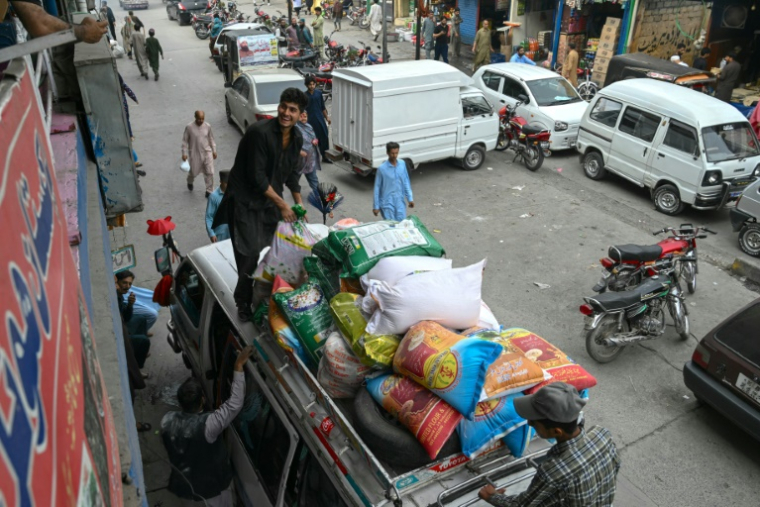 Des habitants chargent des sacs de nourriture sur le toit d'une camionnette au marché de Muzaffarabad, le 2 mai 2025 au Cachemire pakistanais ( AFP / Farooq Naeem )