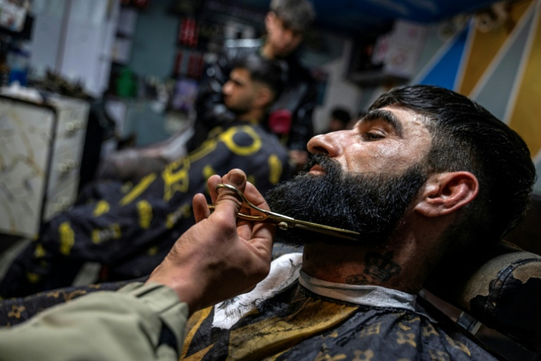 Un homme se fait tailler la barbe dans un salon à Kaboul, le 11 février 2026 ( AFP / Wakil KOHSAR )
