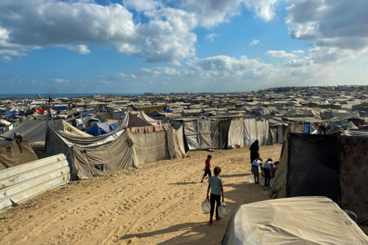 Des enfants palestiniens portent des bidons d'eau dans le camp de déplacés d'Al-Mawasi, dans le sud de la bande de Gaza le 7 août 2025 ( AFP / - )