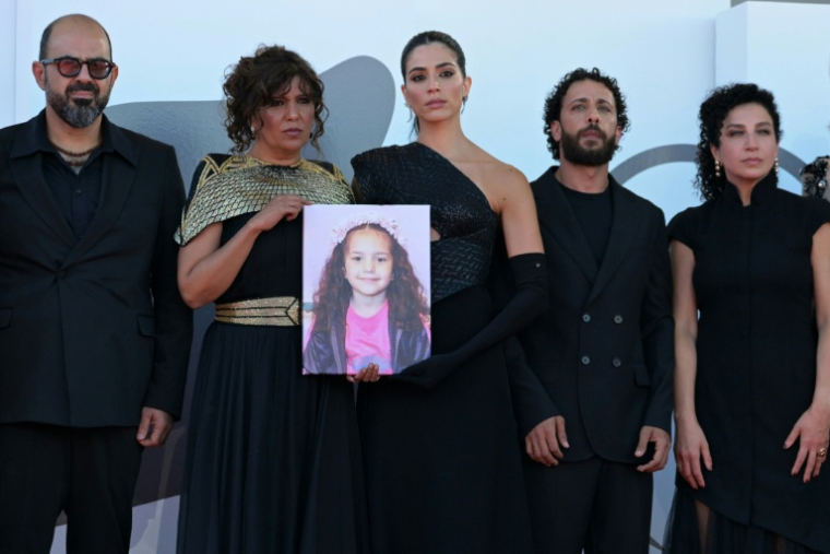 L'acteur israélien Amer Hlehel (g), la réalisatrice franco-tunisienne Kaouther Ben Hania, l'actrice Saja Kilani, l'acteur Motaz Malhees et la comédienne Clara Khoury posent avec un portrait de la fillette palestinienne Hind Rajab, pour la projection officielle du film "The Voice of Hind Rajab", en lice pour le Lion d'or de la 82e Mostra de Venise, le 3 septembre 2025 ( AFP / Tiziana FABI )