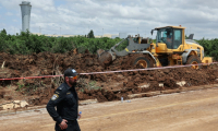 Un bulldozer comble un cratère près d'une route menant à l'aéroport de Tel-Aviv, provoqué par la  chute d'un missile, le 4 mai 2025 ( AFP / Jack GUEZ )