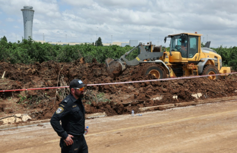 Un bulldozer comble un cratère près d'une route menant à l'aéroport de Tel-Aviv, provoqué par la  chute d'un missile, le 4 mai 2025 ( AFP / Jack GUEZ )