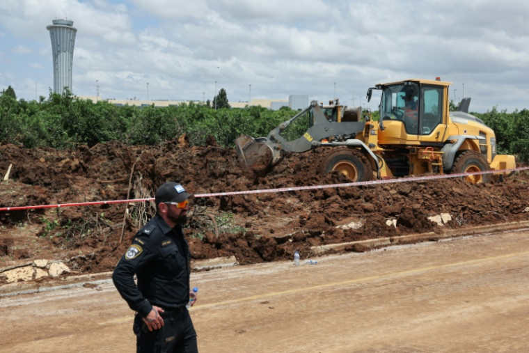 Un bulldozer comble un cratère près d'une route menant à l'aéroport de Tel-Aviv, provoqué par la chute d'un missile, le 4 mai 2025 ( AFP / Jack GUEZ )