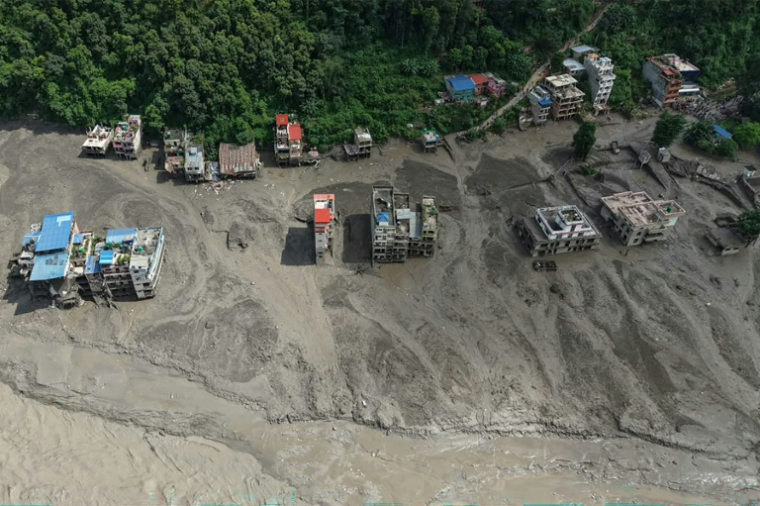 Des maisons sont partiellement submergées par une eau boueuse le long d'une rivière après des crues soudaines à Trishuli Bazar, dans le district de Nuwakot au Népal, le 26 août 2026. ( AFP / Prabin RANABHAT )