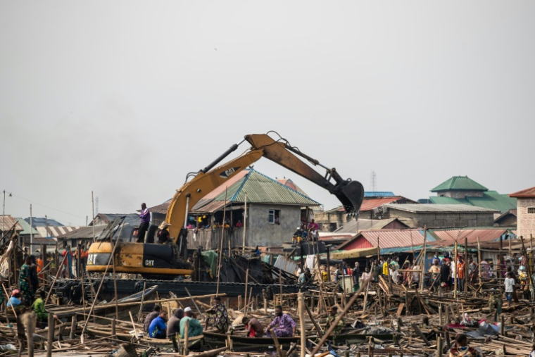 Une engin de chantier démolit des maisons du bidonville flottant de Makoko, le 9 janvier 2026 au Nigeria ( AFP / TOYIN ADEDOKUN )