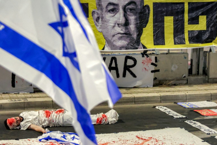 Un manifestant est allongé sur le sol, pour symboliser un otage israélien, lors d'une manifestation anti-gouvernementale organisée par les familles des Israéliens retenus en otages dans la bande de Gaza, le 23 août 2025 ( AFP / Jack GUEZ )